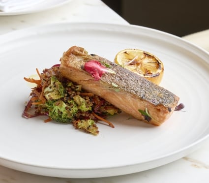 A Salmon dish with charred lemon on a circular white plate at Tula