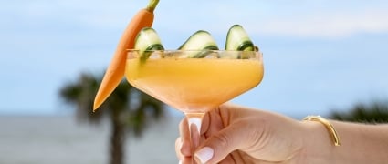 An orange cocktail with a cucumber ribbon and a carrot as garnish at Tula
