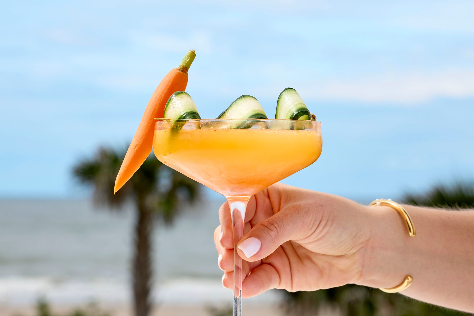 An orange cocktail with a cucumber ribbon and a carrot as garnish at Tula