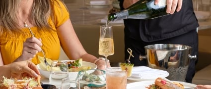 A server pouring champagne at a table while patrons eat at Amrit Ocean Resort