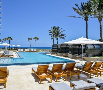 The Amrit Ocean Resort pool with lounge chairs and umbrellas on a sunny day.