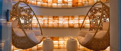 Two hanging wicker chairs with plush cushions in a salt treatment room at Amrit Ocean Resort.