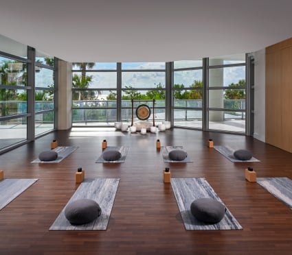 An open yoga studio set up with mats, a gong at the front of the room with large windows overlooking the scenery outside at Amrit Ocean Resort.