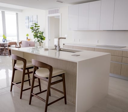 The dining space, floor to ceiling views of Riviera Beach, Florida, and the kitchen in an intracoastal View Wellness Residence at the Amrit Ocean Resort