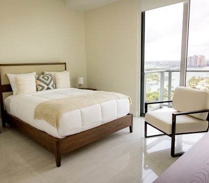 The bedroom with a queen bed and floor to ceiling views of Riviera Beach, Florida in an intracoastal View Wellness Residence at the Amrit Ocean Resort