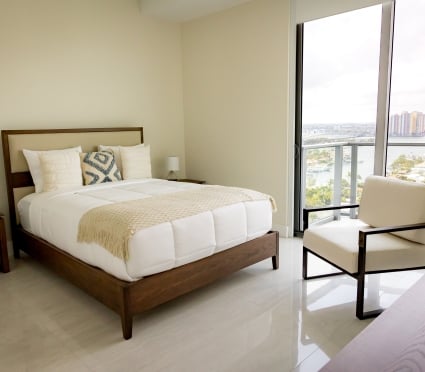 The bedroom with a queen bed and floor to ceiling views of Riviera Beach, Florida in an intracoastal View Wellness Residence at the Amrit Ocean Resort