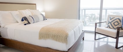 The bedroom with a queen bed and floor to ceiling views of Riviera Beach, Florida in an intracoastal View Wellness Residence at the Amrit Ocean Resort