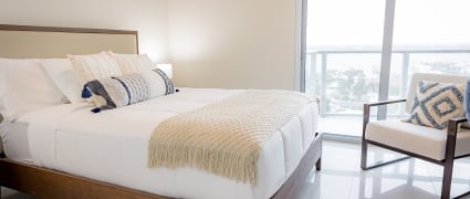 The bedroom with a queen bed and floor to ceiling views of Riviera Beach, Florida in an intracoastal View Wellness Residence at the Amrit Ocean Resort