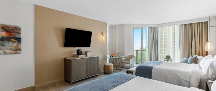 Two Queen beds, a table and a sitting area in an ocean view two queens room at the Amrit Ocean Resort